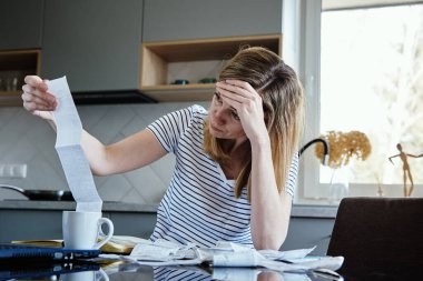 Kadın kağıt faturasına bakıyor ve harcamaları sayıyor, planlama bütçesi ve ev finans yönetimi