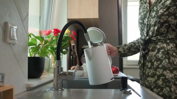 清潔な濾過水を蛇口から電気ケトルに流し 台所で湯を沸かす女性 — ストック動画