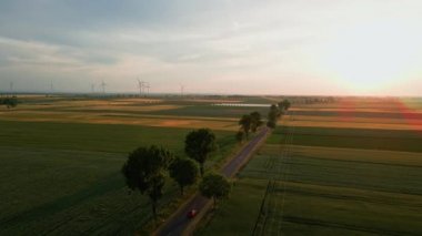 Gün batımına karşı araba trafiği ve yel değirmeni jeneratörü olan yol temiz, yenilenebilir, sürdürülebilir, alternatif enerji kavramı