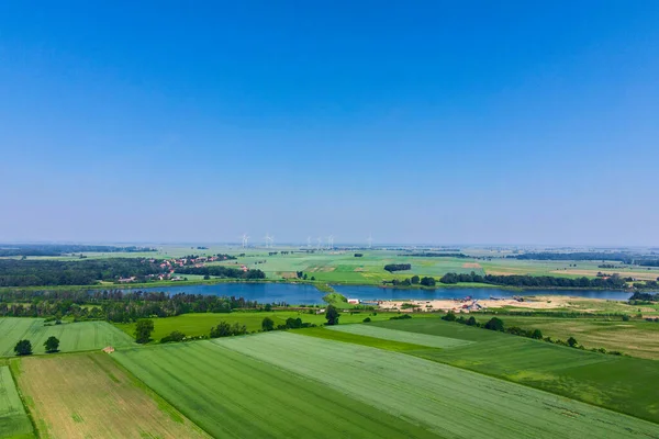 Windmill turbine generator against blue sky in countryside with green fields and lake, Concept of clean, renewable, sustainable, alternative energy