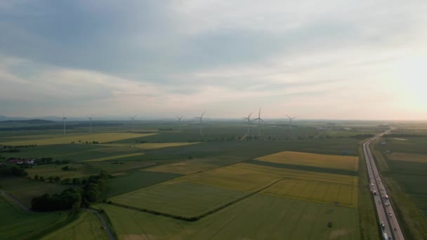 汽车和风力涡轮机在夕阳西下的公路 可再生 可持续 替代能源的概念 — 图库视频影像