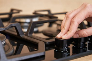 Kadın eli gaz kontrol panelinde ısıyı ayarlıyor, kadın gaz sobası kullanıyor, modern ev aletleri...