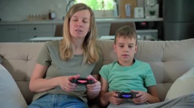 Oğlan ve anne evde video oyunu oynuyor, aile birlikte vakit geçiriyor, mutlu bir ilişki, online eğlence ve boş zaman aktivitesi.,