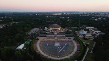 İnsanlar Polonya 'nın Wroclaw şehrindeki Hala Stulecia' da multimedya çeşmesinin yanında dinleniyorlar. Centennial Hall, UNESCO Dünya Mirası Alanına sahip şehir manzarası