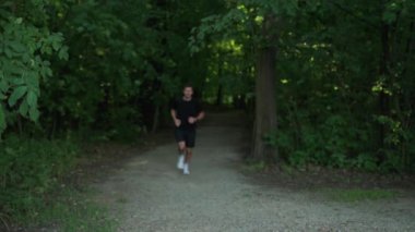 Male runner jogging at park and looking at fitness watch. Sport wearing man running outdoors. Fitness, cardio and healthy lifestyle concept