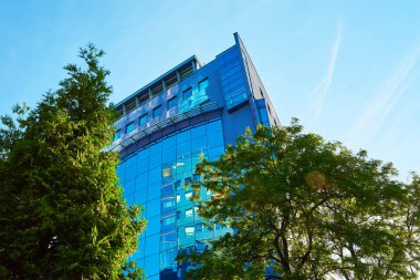 Yeşil ağaçlarla kaplı cam cephe, iş dünyası için modern ofis binası, ikametgah çağdaş