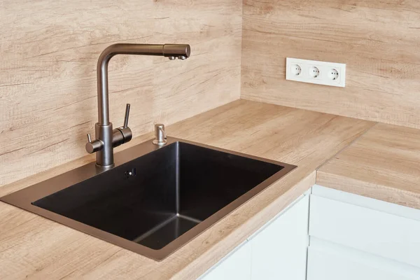 Black stainless sink with tap in kitchen interior