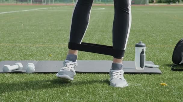 Female Legs Doing Workout Exercise Elastic Ripe Band Green Grass — Vídeo de stock