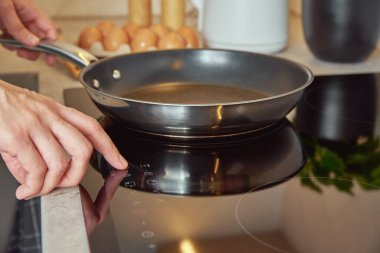Modern mutfak aletleri, indüksiyon sobasını çelik tavayla açmak, parmak sensör düğmesine basmak, indüksiyon ya da elektrikli hob.
