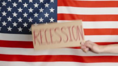 Concept of economic crisis, recession and inflation in USA, Woman hand show cardboard sheet with word recession against american flag, Rising prices for consumer goods and services