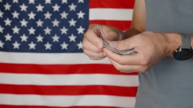 Male hands counting 100 usd banknotes agains american flag, Unrecognizable man calculating cash dollars