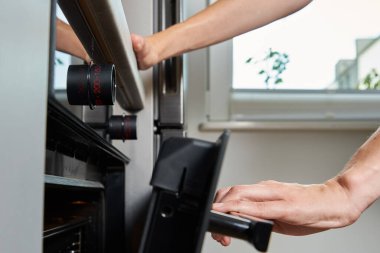 Kadın eli elektrikli fırın kapısı, elektrikli fırın kullanan kadın, modern ev aletleri.