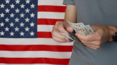 Male hands counting 100 usd banknotes agains american flag, Unrecognizable man calculating cash dollars