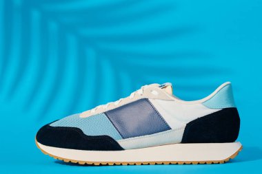 Mavi arka planda şık ayakkabılar, bitki gölgeleri, şık spor ayakkabılar, şık moda minimalizm konsepti