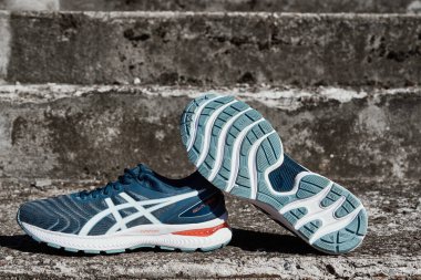 Asics Gel Nimbus running shoes at concrete stairs background, Pair of Asics sport sneakers for jogging. Katy Wroclawskie, Poland - August 07, 2022