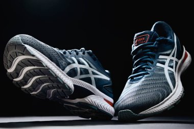 Flying Asics Gel Nimbus shoes on black background, Creative shot of Asics sport sneakers for jogging. Katy Wroclawskie, Poland - August 07, 2022