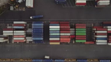 Process of loading MAERSK containers in terminal, Unloading containers in warehouse on railroad platform with cranes and forklifts, aerial view