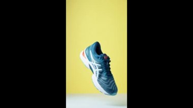 Flying Asics Gel Nimbus shoes on yellow background, Creative shot of Asics sport sneakers for jogging
