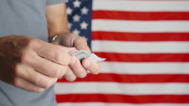 Male hands counting 100 usd banknotes agains american flag, Unrecognizable man calculating cash dollars