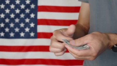 Male hands counting 100 usd banknotes agains american flag, Unrecognizable man calculating cash dollars