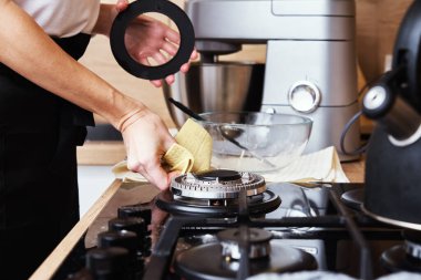Cleaning gas stove. Woman cleans kitchen gas hob with cleaning sponge, Daily chores and housework