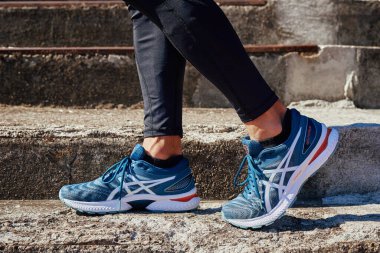 Male sprinter wearing Asics Gel Nimbus at concrete stairs background. Sport and fitness runner athlete training at stadium. Katy Wroclawskie, Poland - August 07, 2022