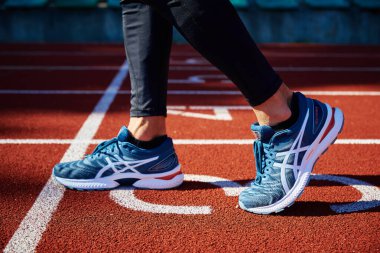 Male sprinter wearing Asics Gel Nimbus at running track. Sport and fitness runner athlete training at stadium. Katy Wroclawskie, Poland - August 07, 2022