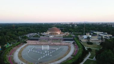 İnsanlar Polonya 'nın Wroclaw şehrindeki Hala Stulecia' da multimedya çeşmesinin yanında dinleniyorlar. Centennial Hall, UNESCO Dünya Mirası Alanına sahip şehir manzarası