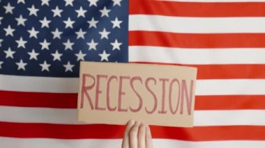 Concept of economic crisis, recession and inflation in USA, Woman hand show cardboard sheet with word recession against american flag, Rising prices for consumer goods and services