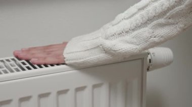 Woman adjusting temperature on heating radiator, Energy crisis concept in Europe, Rising costs in private households for gas bill due to inflation and war