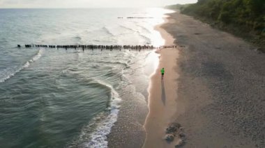 Aerial view of man jogging along sea beach at morning, Athlete training running for health care
