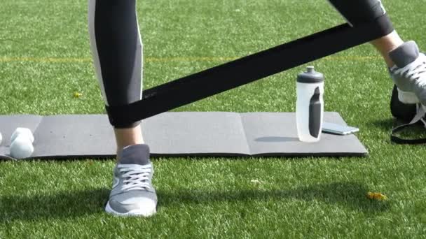 Female Legs Doing Workout Exercise Elastic Ripe Band Green Grass — Stockvideo