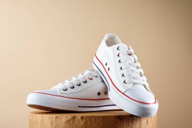 Bej arka planda bir çift şık ayakkabı. Fotokopi alanı olan spor ayakkabıları, yaz ayakkabıları konsepti