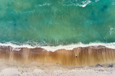 Sand beach with sea waves, top view. Summer vacation and travel concept. Beautiful coastline with blue sea and sand beach, aerial view