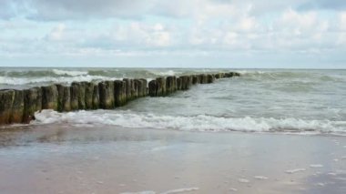 Baltic sea seachore with waves, breakwater and beautiful cloudy sky without people, Summer travel and vacation in Poland