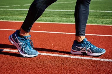 Male sprinter wearing Asics Gel Nimbus at running track. Sport and fitness runner athlete training at stadium. Katy Wroclawskie, Poland - August 07, 2022