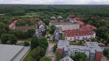 Küçük bir kasabada, hava manzaralı bir yerleşim yeri. Yeşil parkın yakınında park etmiş arabalı evler.