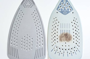 Old iron with damaged soleplate and new modern iron on white background, Maintenance and care of modern household appliances