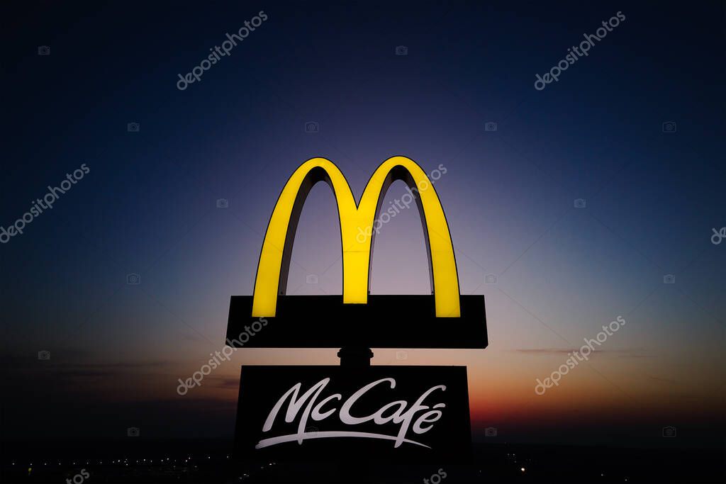 Glowing McDonalds restaurant sign against night sky. Logo of McCafe biggest restaurant chain McDonalds in world. Katy Wroclawskie, Poland - March 20, 2022