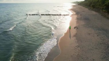 Aerial view of man jogging along sea beach at morning, Athlete training running for health care