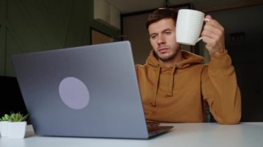 Evden çalışan bir adam. Oturma odasında uzaktan çalışan ve dizüstü bilgisayar kullanan serbest çalışan bir erkek.