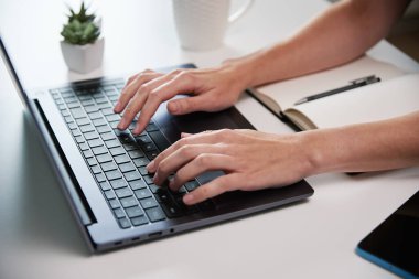 Evden çalışan bir kadın. Oturma odasında uzaktan çalışan ve dizüstü bilgisayar kullanan serbest çalışan, klavyede yazan bir kadın.