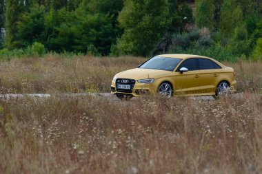 Sonbahar asfaltlı bir yolda yüksek hızda giden sportif sarı bir sedan. Audi RS3 Sportback Quattro arabası. Nikolaev, Ukrayna - 26 Eylül 2021