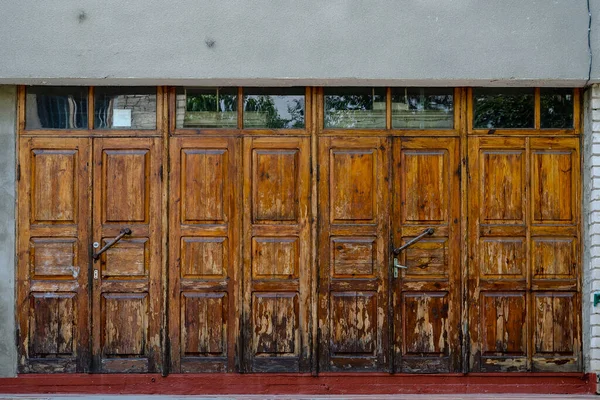 Old wooden doors in a row. Brown weathered doors. Entrance to an — Stock Photo, Image