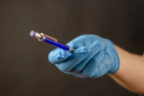 Defocused schot van artsen hand in blauw medische handschoen met penci — Stockfoto