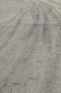 Siyah lastik izleri olan gri asfalt. Kırıkları olan eski bir köy yolu. Otobanda virajda kavisli tekerlek izleri.