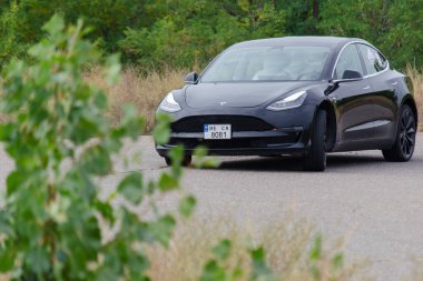 Tesla model 3 uzay versiyonu. Siyah elektrikli spor araba yüksek hızda bir yol köşesine doğru gidiyor. Ukrayna, Nikolaev - 26 Eylül 2021