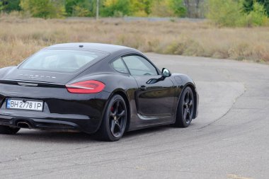 Siyah spor araba asfalt yolda gidiyor. Porsche Cayman GT4 RS yüksek hızda. Hareket bulanıklığı. Nikolaev, Ukrayna - 09 26 2021