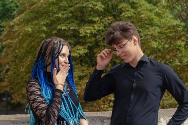 Genç bir adam çekici bir kadınla flört ediyor. Gözlüklü bir adam. Uzun mavi örgülü bir kadın. Dışarı çıkın. Defocus, bulanıklık, gürültü, tahıl etkisi.