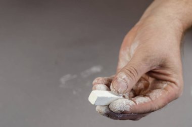 Yetişkin bir adamın eli bir parça beyaz tebeşir tutuyor. Seçici Odaklanma.